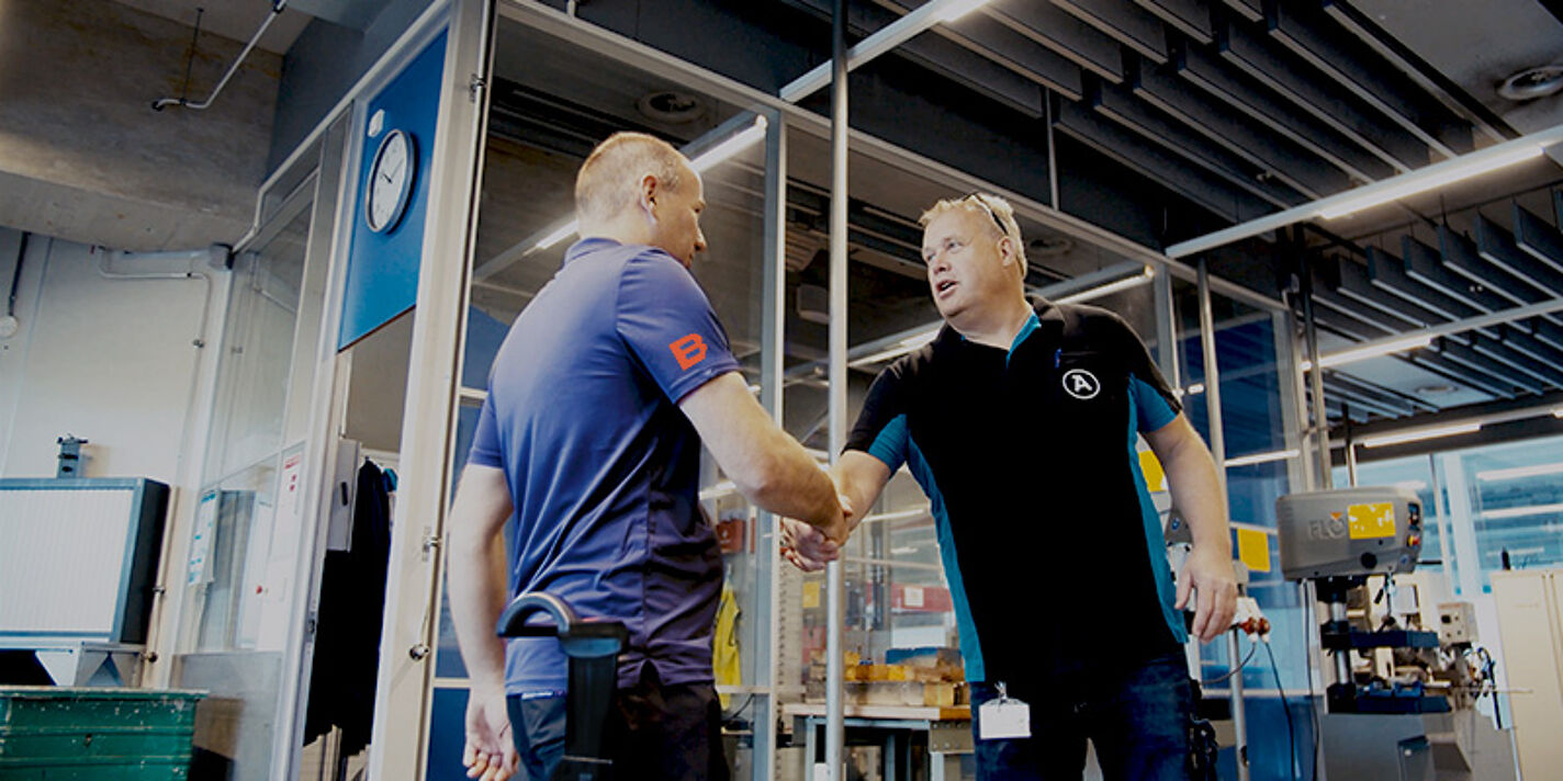 BUS-specialist en klant geven elkaar een hand in een industriële omgeving