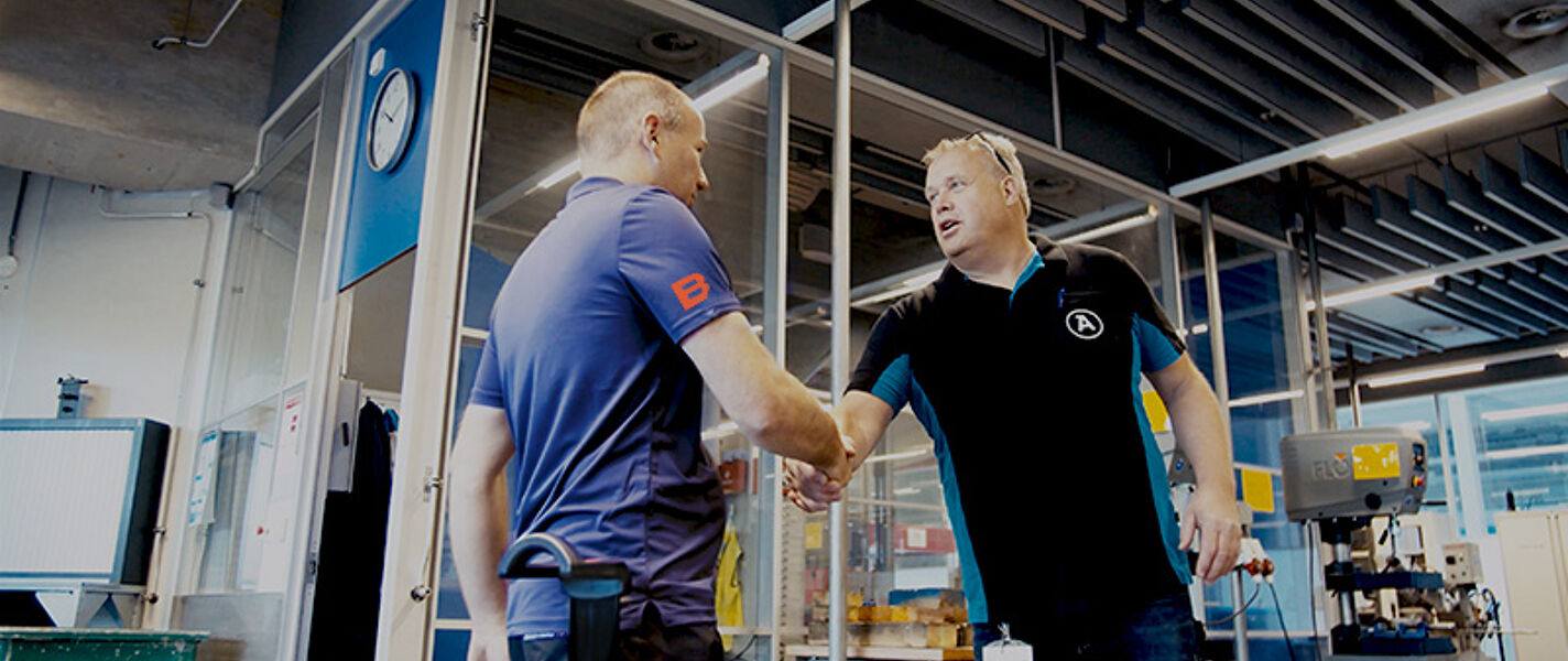 BUS-specialist en klant geven elkaar een hand in een industriële omgeving
